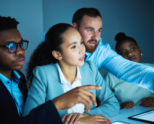 Side view of many IT professionals looking at computer screen